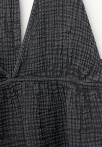 Tissu gris foncé avec un motif texturé et froissé ; présente un décolleté en V et une couture de taille froncée pour plus de structure.