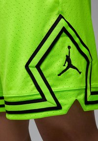 Shorts de basket-pour homme vert vif, avec une texture perforée, des accents noirs et un logo en silhouette sur un élément de design.