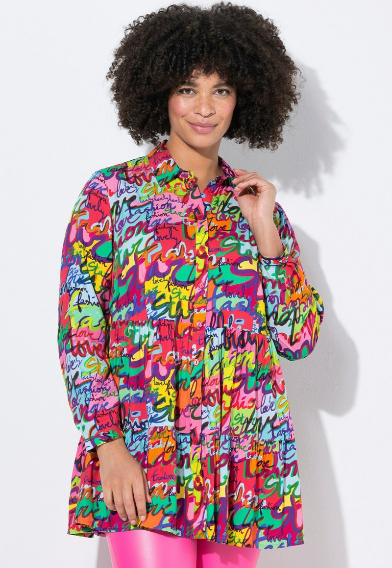 Bunt gemustertes Shirtkleid mit auffälligen Schriftzügen in Pink, Grün und Gelb; lange Ärmel und Knopfleiste.