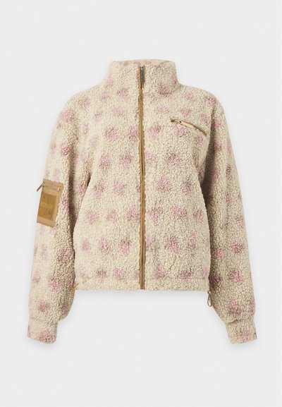 Veste en polaire sherpa crème avec des pois floraux roses, fermeture éclair intégrale, poches zippées poitrine et manches, et col montant.