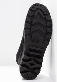 Semelle extérieure en caoutchouc noir avec un motif en zigzag, présentant une surface texturée et des bords renforcés. Logo "PALLADIUM" embossé sur le côté.