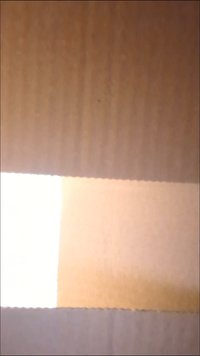 Texture di cartone marrone con strisce orizzontali di beige chiaro e bianco, con un bordo tagliato ondulato nella parte inferiore.