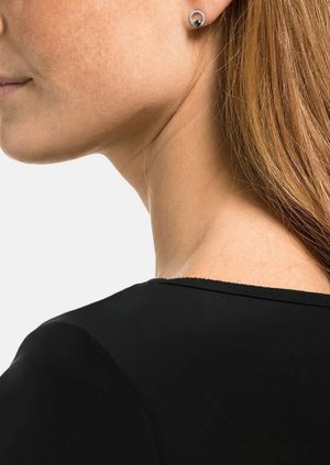 Silberne Ohrringe mit rundem Design, featuring einem dunklen zentralen Stein, umgeben von einem funkeltenden Rand, getragen von einer Person mit langen Haaren.