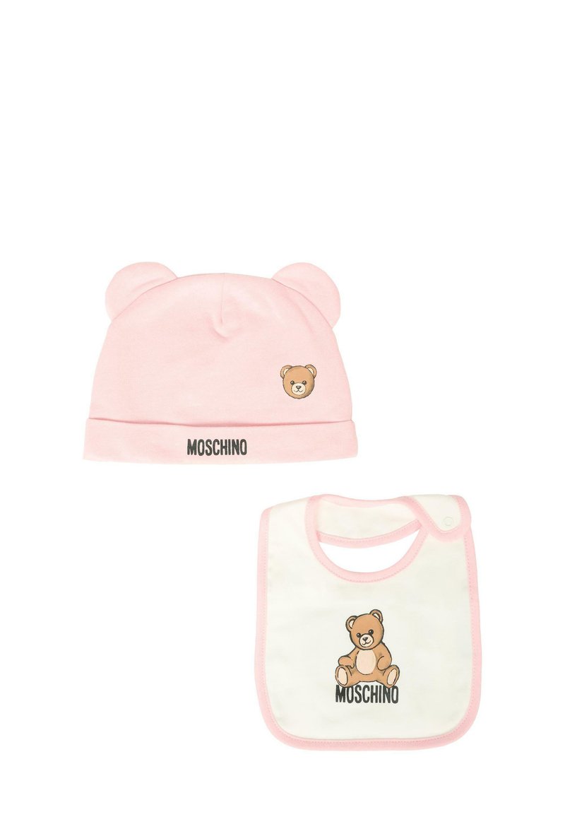Różowa bawełniana czapka z uszami misia i haftowanym logo misia, zestawiona z białym śliniakiem z podobnym wzorem misia i różowym wykończeniem.