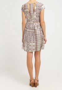 Robe à motif floral en tissu léger, avec manches courtes, ouverture en goutte d'eau au dos, et une jupe évasée à couches superposées.