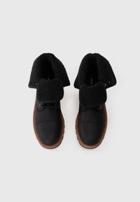 Zapatos negros de cordones con parte superior sintética texturizada, un acogedor cuello de forro polar negro y una suela de goma marrón. Diseño de puntera redonda.