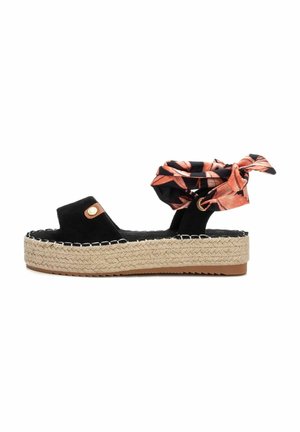 Sandalia de espadrille de ante negro con suela de yute trenzado, que presenta un lazo de tela con estampado floral naranja y costuras en contraste.