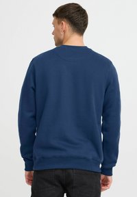 Sudadera azul marino de manga larga con puños de canalé. Presenta un cuello redondo y un acabado texturizado. Diseño simple sin gráficos.
