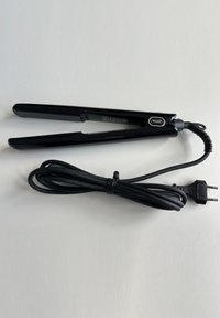 Zwarte haarstyler met een stroomkabel en stekker, rustend op een lichte ondergrond. Het merkimago is zichtbaar aan één kant.