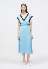 Μπλε μεταξωτό φόρεμα με λαιμόκοψη σε σχήμα V και μαύρη δαντέλα στο τελείωμα, κοντά μανίκια και ζώνη στη μέση, που φτάνει μέχρι το μέσο της γάμπας. Λεία υφή.