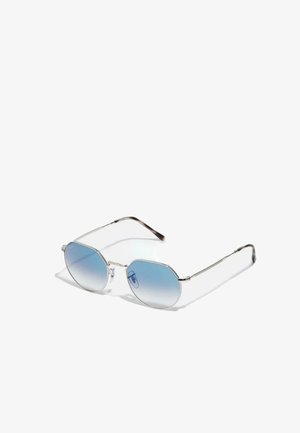 Gafas de sol octagonales con un marco de metal plateado, lentes degradados en azul y brazos transparentes. Presenta un diseño minimalista y detalles de alambre.