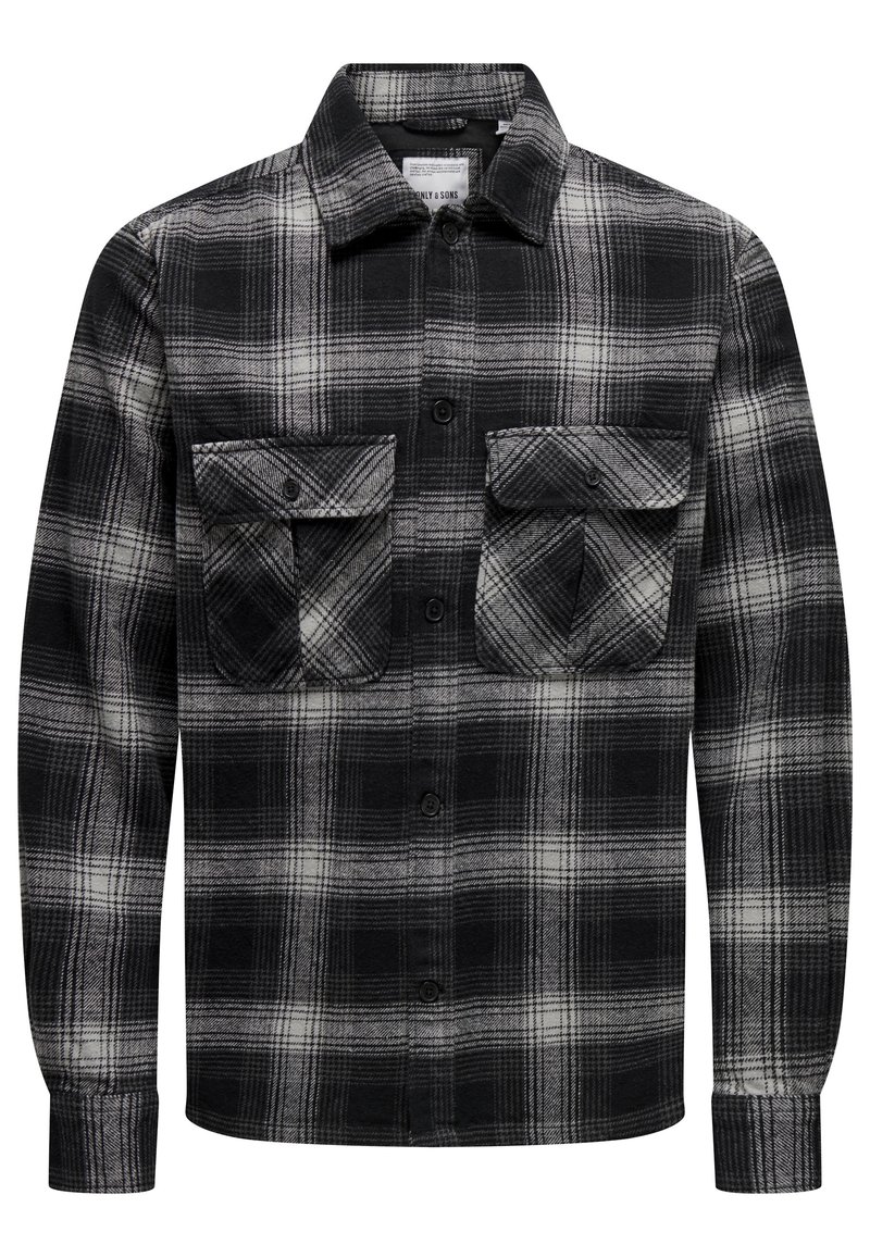 Camisa de cuadros en blanco y negro hecha de franela; presenta dos bolsillos en el pecho, un cuello y cierre de botones; mangas largas con puños abotonados.
