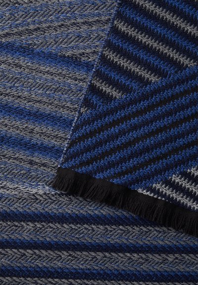 Tecido tecido com riscas diagonais em tons de azul, cinza e preto. A borda apresenta um detalhe de franjas pretas.