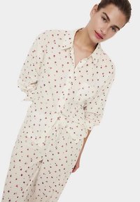 Hvid skjorte med knapper og matchende bukser med et lille blomsterprint i pink og lilla. Letvægtsstof med afslappet pasform og lange ærmer.