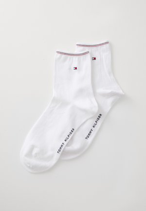 Valged puuvillased sokid, millel on väike logo, punased ja sinised triibud ülaservas ning "TOMMY HILFIGER" trükituna küljele.
