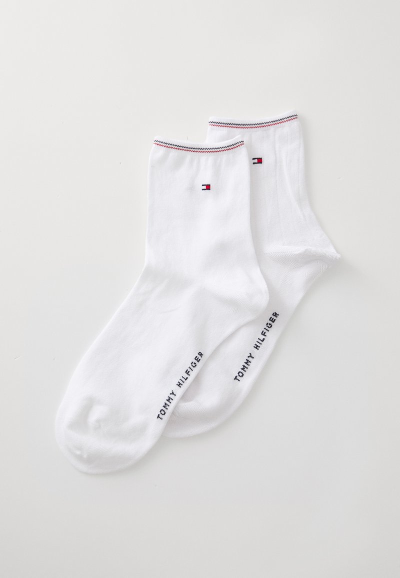 Calcetines de algodón blancos con un pequeño logo, franjas rojas y azules en la parte superior, y "TOMMY HILFIGER" impreso en el lateral.