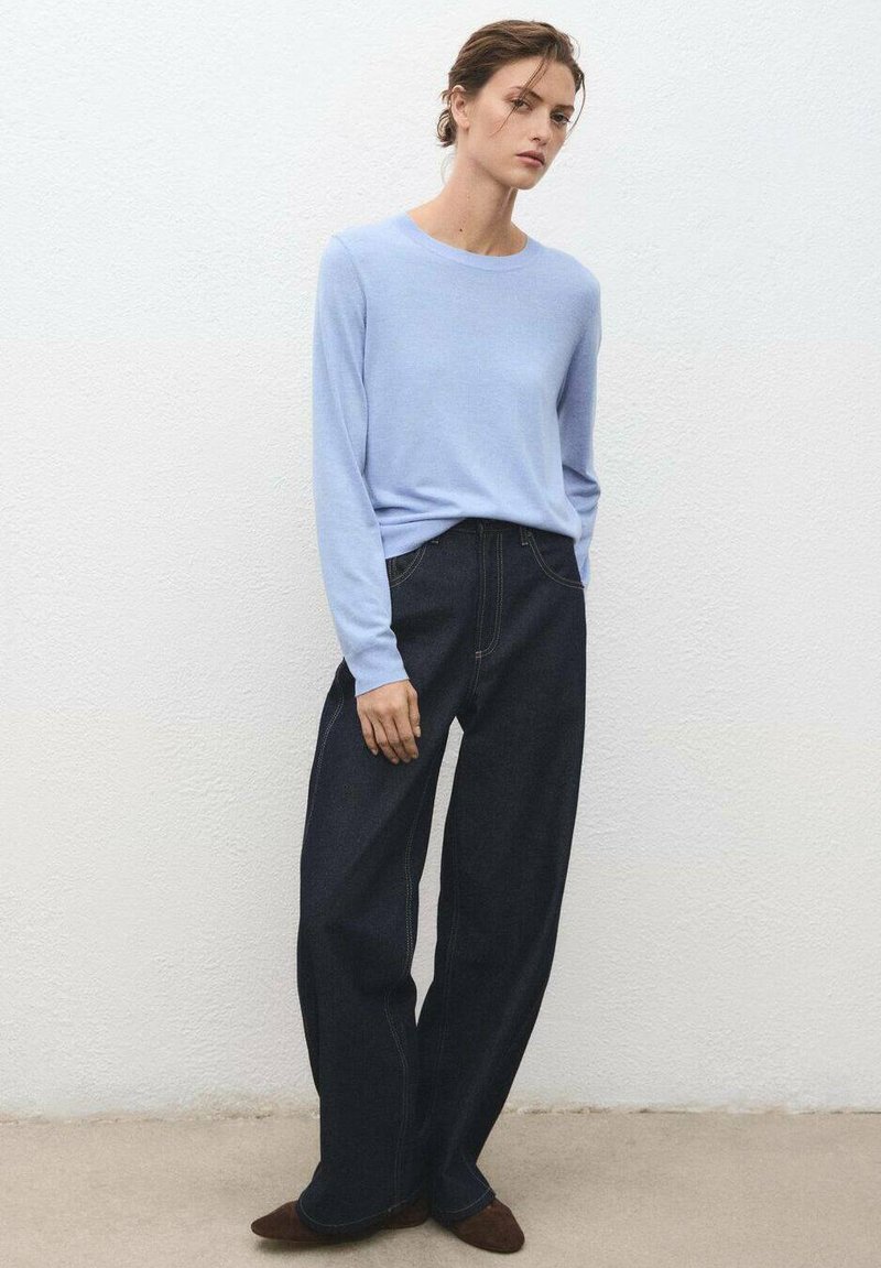 Light blue long-sleeve sweater paired with dark denim wide-leg pants. Sweater has a crew neckline; pants feature visible stitching and pockets.