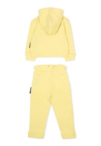 Żółta bluza z kapturem i pasującymi spodniami dresowymi. Gładka tkanina, elastyczny pasek w talii i ściągacze na nogawkach. Prosty design.