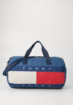 Sac de voyage en denim avec des poignées bleu marine, présentant un design en blocs de couleurs blanc, rouge et bleu. "TOMMY JEANS" imprimé en blanc sur une bande bleue.