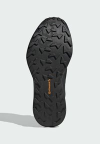 Suola di scarpa in gomma nera caratterizzata da un design testurizzato con motivi angolari per una migliore aderenza. Include un distintivo logo arancione Continental.