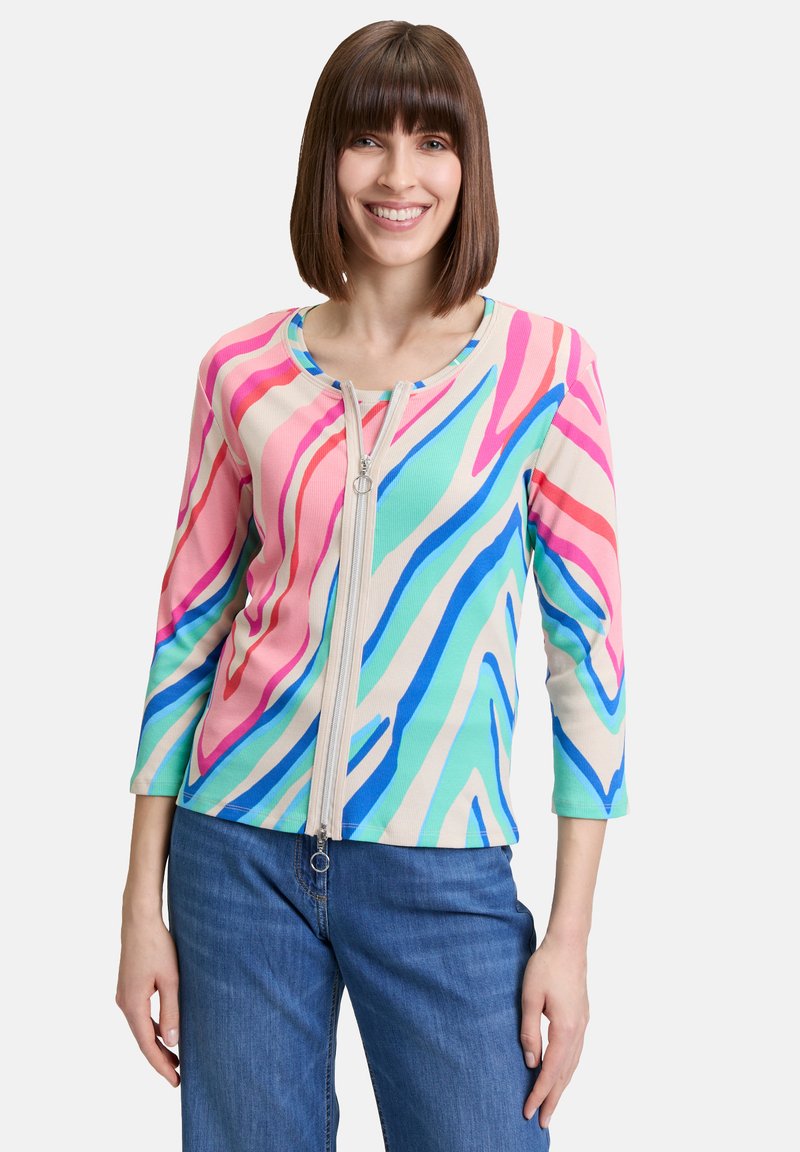 Haut côtelé multicolore avec fermeture éclair sur le devant, manches trois-quarts et motif ondulé dans des teintes de rose, bleu et vert.