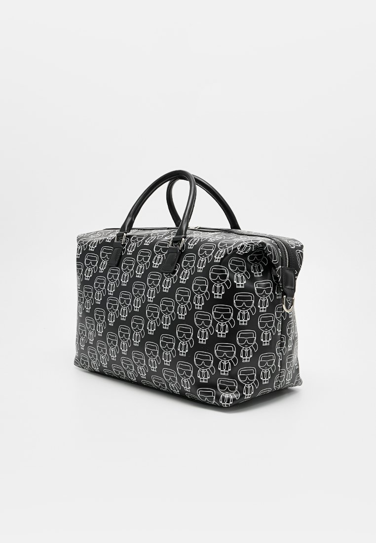 Bolso negro con estampado de personaje de dibujos animados blanco, forma rectangular, material sintético, doble asa negra, cierre superior con cremallera, textura lisa.