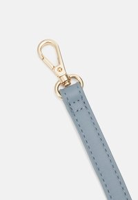 Correa de cuero azul claro con una textura suave, con un clip de metal dorado y un anillo circular para su sujeción.