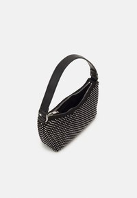 Sac à main noir avec des clous argentés sur toute la surface, ouverture zippée et une bandoulière lisse noire, présenté sur un fond blanc.