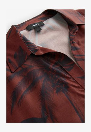 Camicia a maniche corte con base marrone e motivo a foglie di palma nere. Presenta un colletto a punta e una texture di tessuto morbido e liscio.