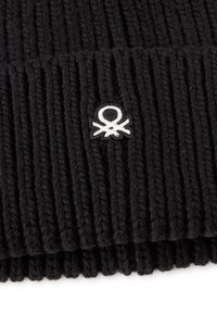 Gorro de lana negro con textura acanalada. Presenta un pequeño logotipo bordado en blanco con forma de pulpo en la parte frontal.