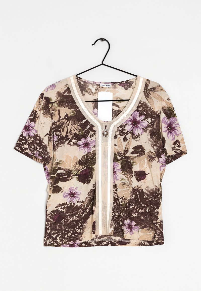 Korte mouw beige blouse met paarse bloemen- en bladerenpatroon, V-hals trim en decoratieve broche, hangend aan een zwarte hanger.