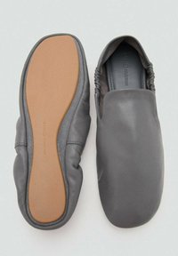Szare skórzane buty wsuwane o miękkiej, elastycznej konstrukcji, z zaokrąglonym noskiem i jasnobrązową gumową podeszwą. Marszczone zdobienia na krawędziach.