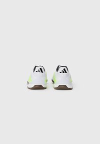 Pair of white and neon green Adidas sports shoes shown from the back on a plain white background.