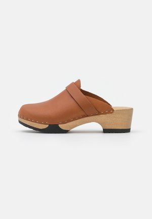 Zueco de cuero marrón con suela de madera y agarres de goma negra, con un tacón bajo y diseño abierto trasero sin cierre.