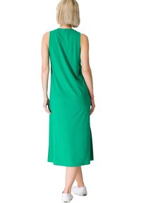 Femme aux cheveux blonds courts portant une robe midi verte sans manches et des baskets blanches, vue de dos sur fond blanc.