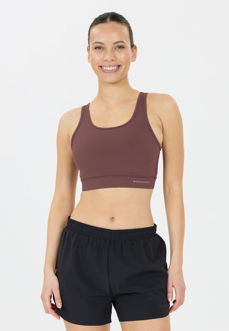 Bruine sportbeha met een strakke pasvorm en brede bandjes, gecombineerd met zwarte sportshorts met een elastische tailleband.