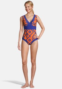 Maillot de bain une pièce avec un motif géométrique orange vif et marine, décolleté en V profond et larges bretelles. Tissu texturé.
