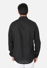 Camisetta nera a maniche lunghe in lino leggero, con collo standard, polsini con bottone e orlo curvo sul retro.