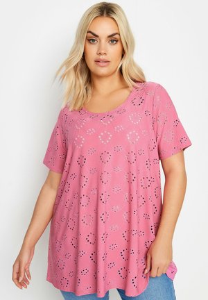 Haut rose à manches courtes avec une coupe ample, présentant un motif découpé et un col rond, fabriqué en tissu léger. Style décontracté.