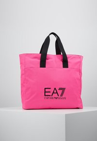 Růžová nylonová taška na rameno s černými držadly a potiskem loga "EA7 EMPORIO ARMANI" na přední straně. Má jednoduchý obdélníkový tvar.