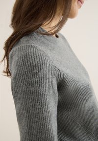 Harmaa ribbed-neule, jossa on pyöreä pääntie ja teksturoitu neulekuvio, istuvat hihat ja pehmeä, lämmin ilme.