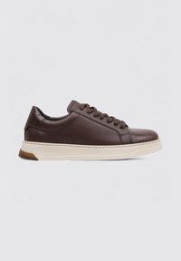 Zapatilla de cuero marrón con punta redondeada, parte superior texturizada y suela de goma cremosa gruesa. Presenta cordones marrones a juego y un diseño minimalista.