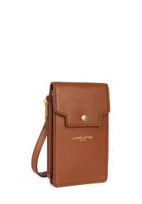 Bruine leren portemonnee met gouden hardware, een flapsluiting en een ritsvak. Voorzien van een polsband en een geperst merkl Logo.
