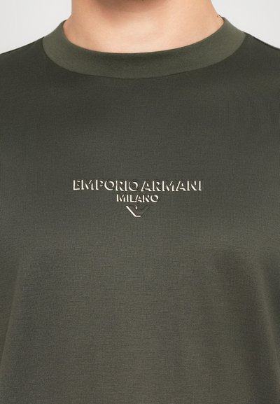 Zöld crewneck póló, középen fehér "Emporio Armani Milano" logóval a mellkason.
