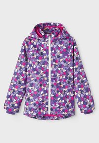 Lila Jacke mit Kapuze, die ein buntes Herzmuster aufweist. Sie hat einen Frontreißverschluss und elastische Bündchen und besteht aus einem leichten Stoff.