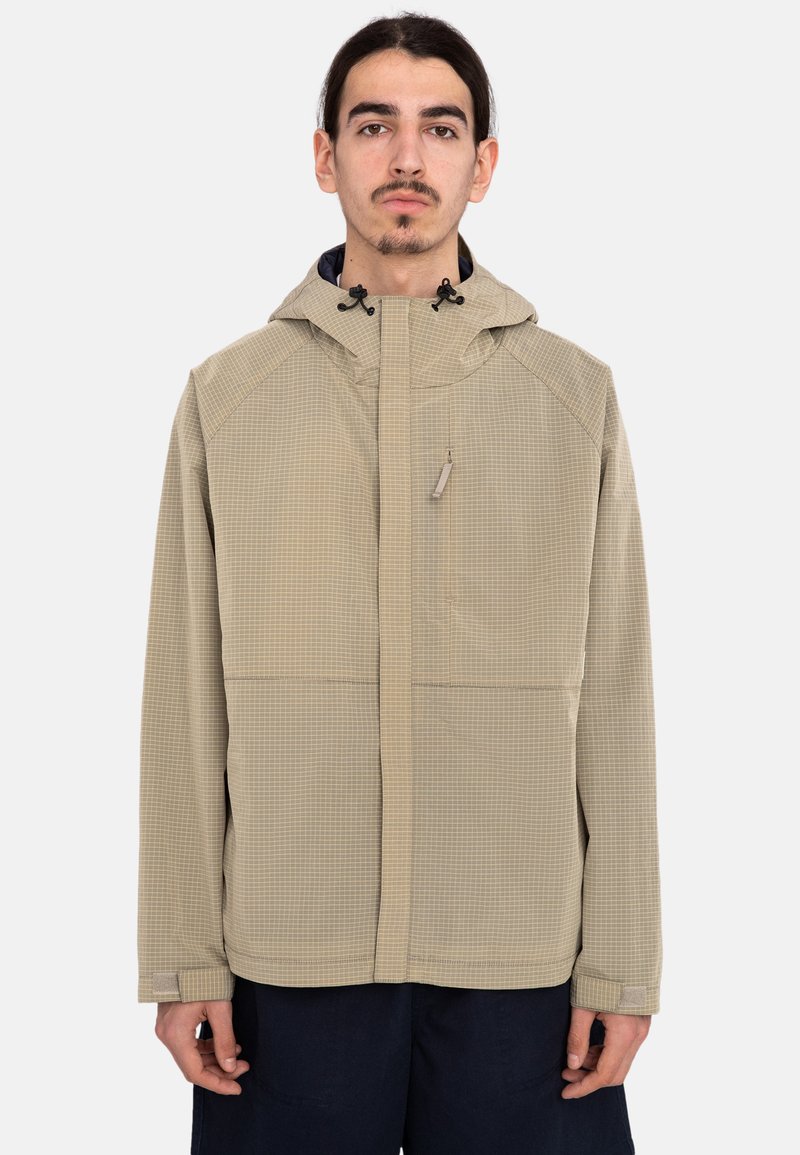 Chaqueta beige con un patrón y capucha, con cremallera frontal, cordones ajustables y bolsillos, hecha de un material ligero.