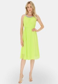 Jasnozielona sukienka w neonowym odcieniu z fałdowanym wzorem, zdobiona koralikami dekoltem i paskiem do związania w talii. Ażurowa tkanina z falbaniastym wykończeniem.