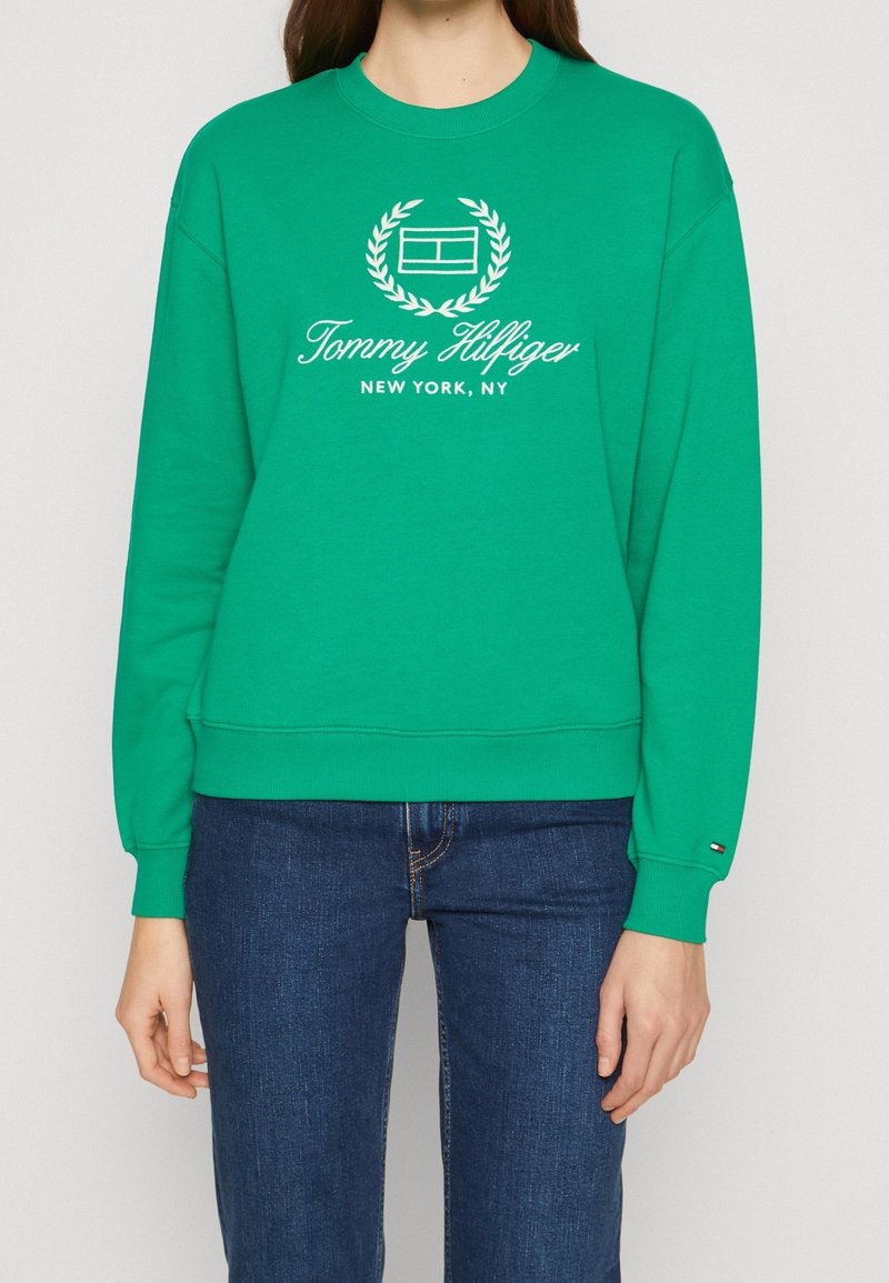 Felpa verde in cotone, con scollo a girocollo e maniche lunghe. La parte frontale presenta un logo e del testo bianchi, con polsini e orlo a costine.
