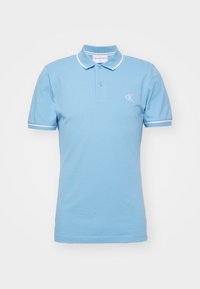 Jasnoniebieska koszulka polo z kołnierzykiem, krótkimi rękawami i białymi wykończeniami na rękawach. Posiada małe, białe logo "CK" na piersi.