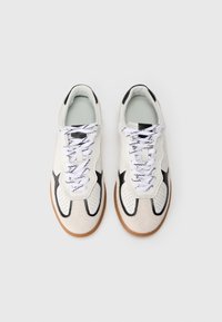 Sport sneakers with a white upper, black accents, and perforated detailing. Features white laces and a textured gum rubber sole.